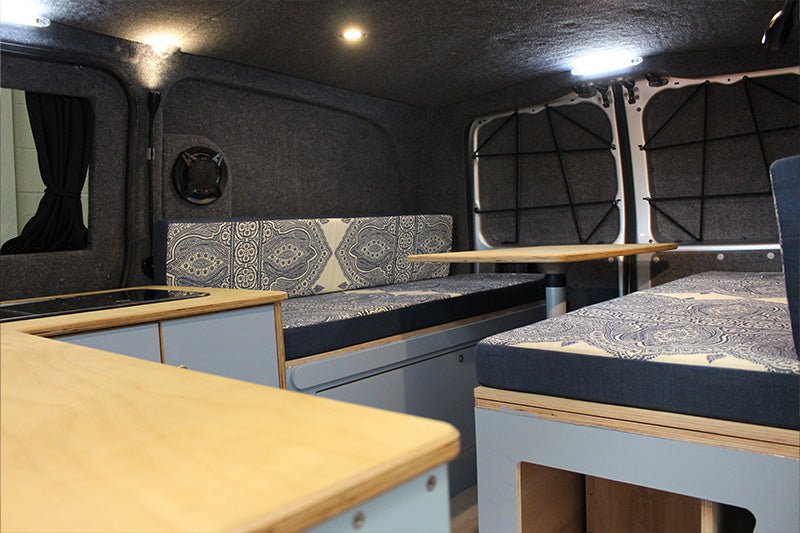 Interior of a converted Mercedes Vito camper van, showing pale blue furniture.
