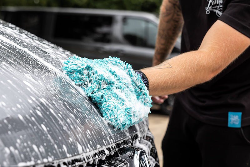 Closeup of a man cleaning a VW campervan with a cloth
