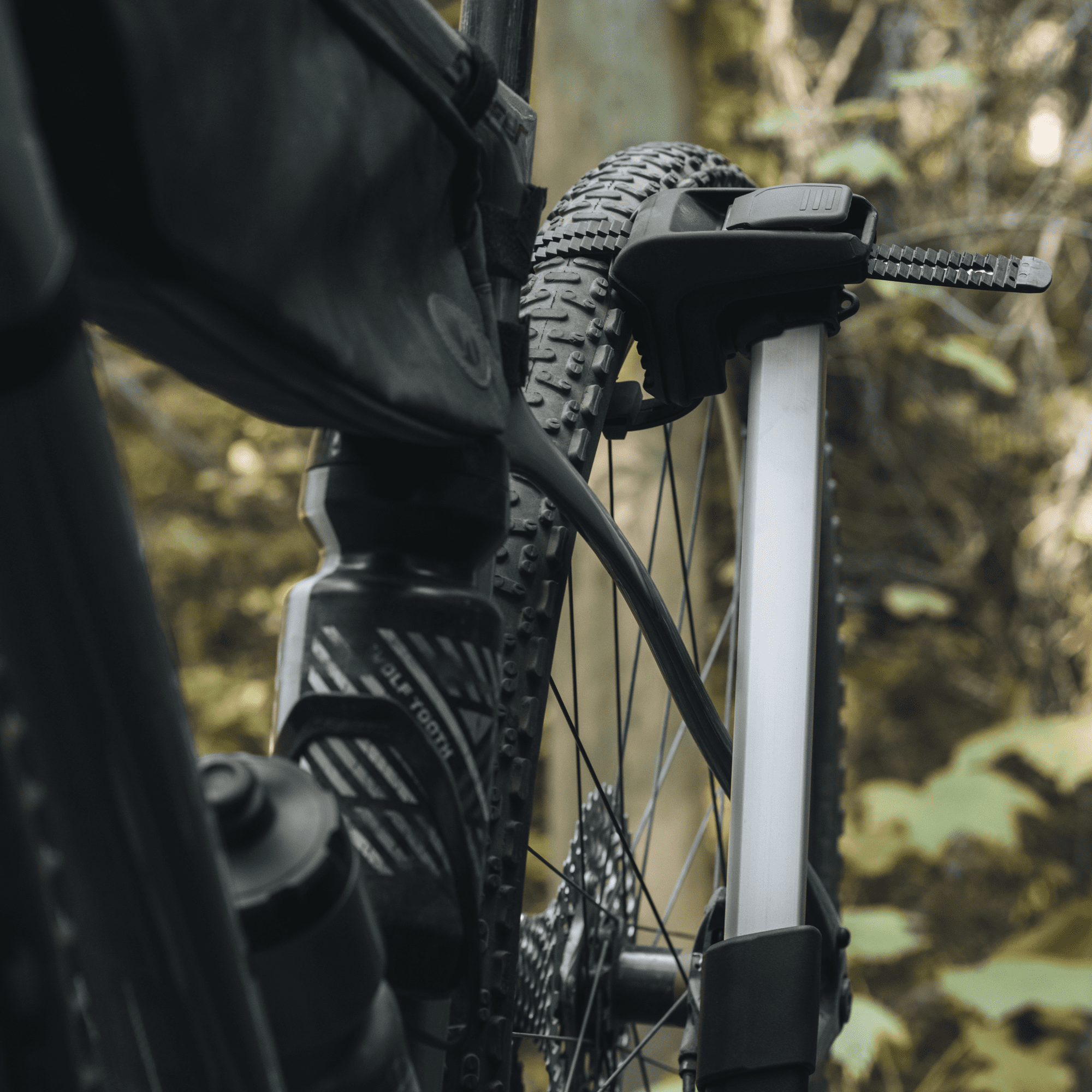 Close-up of a black mountain bike wheel secured to a silver Thule Epos bike rack with a strap.