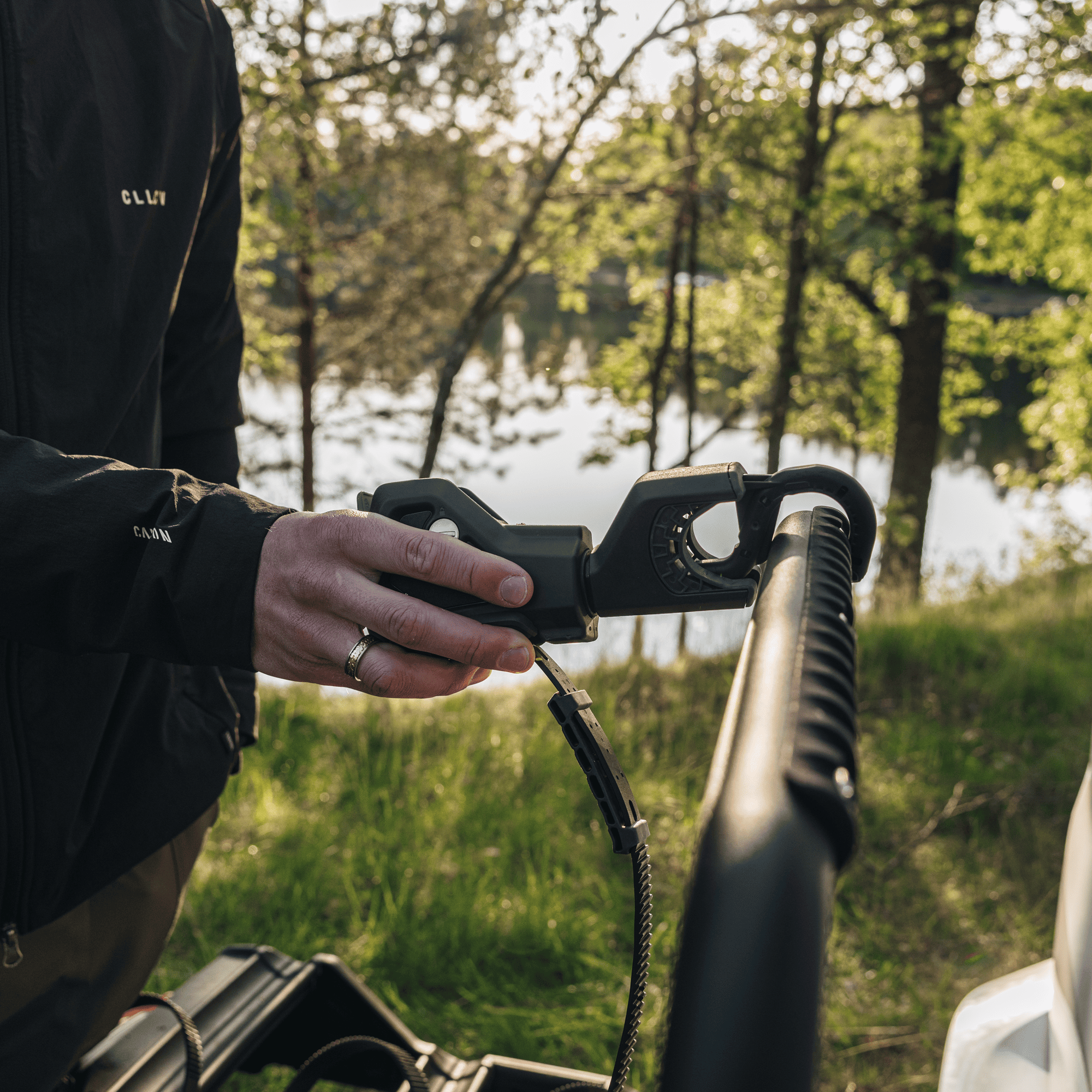 Person adjusting the black Thule VeloSpace 3 bike rack's towbar attachment mechanism outdoors.