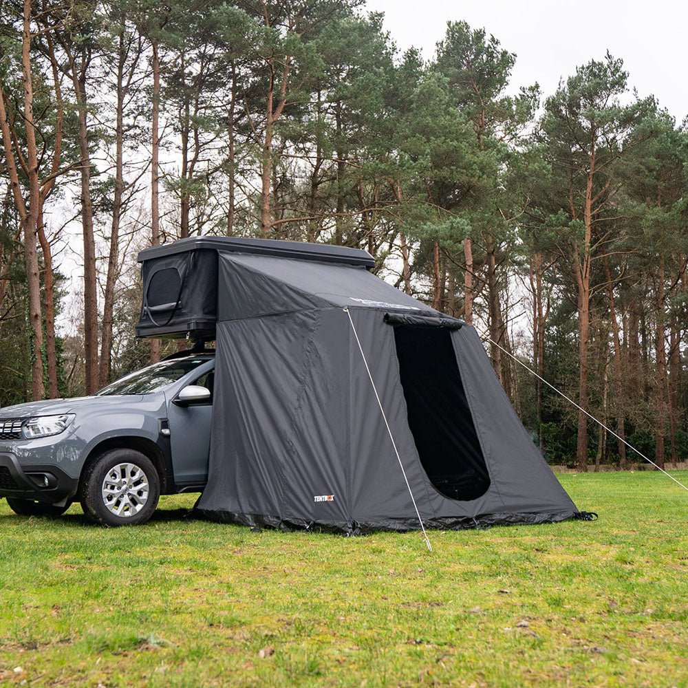 Dark grey TentBox Classic Living Pod attached to a rooftop tent on a grey SUV, set in a forest.