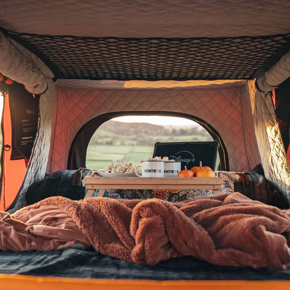 Quilted peach thermal lining installed inside a TentBox Classic 2.0, with bedding, mugs, and snacks.