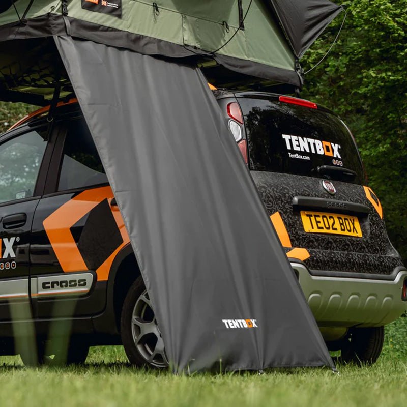 Black TentBox Lite Windbreak attached to a green roof tent on a black car.
