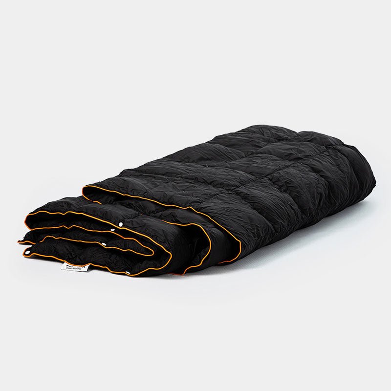 Black quilted synthetic down blanket with orange trim, folded for portability.