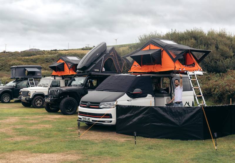 collection of vehicles in a field with orange TentBox tents on top