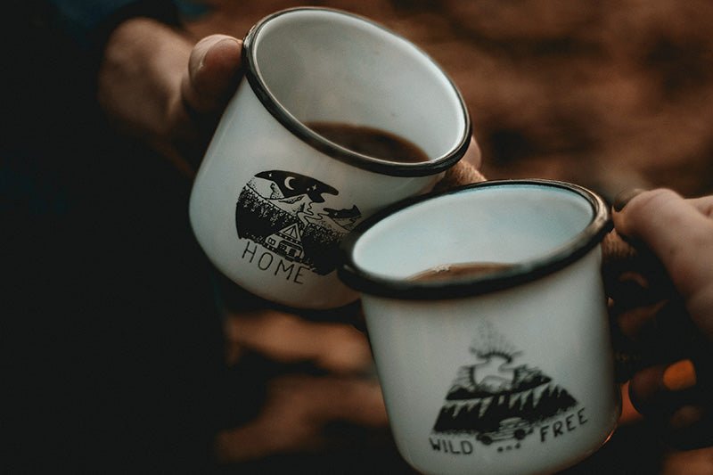 closeup of two hands holding two camping coffee mugs
