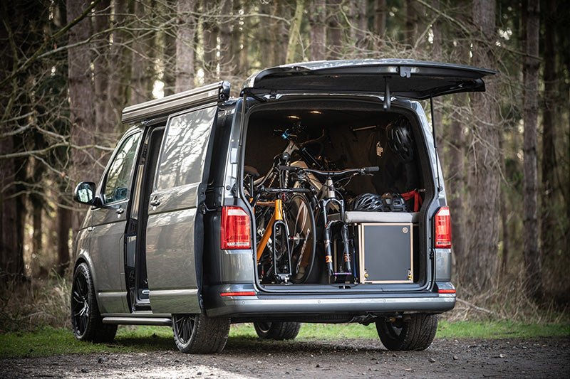 A van with the tailgate open and mountain bikes stored inside