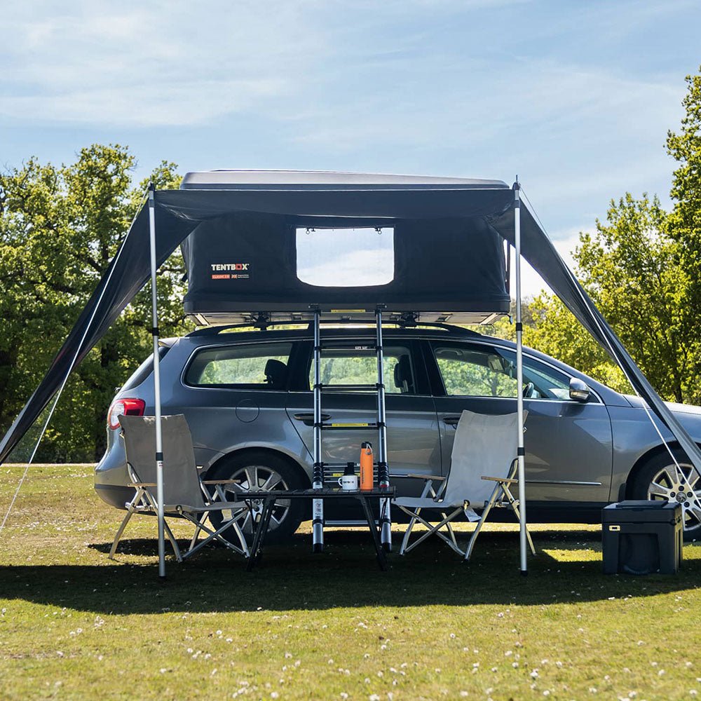 Black Classic Tunnel Awning attached to a car roof tent, providing shaded outdoor space with camping chairs and table.