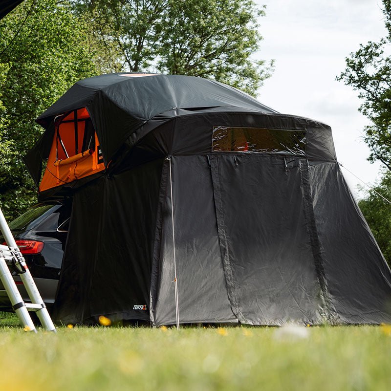 Black Lite XL Ultimate Bundle rooftop tent with orange interior, attached to a car in a grassy outdoor setting.