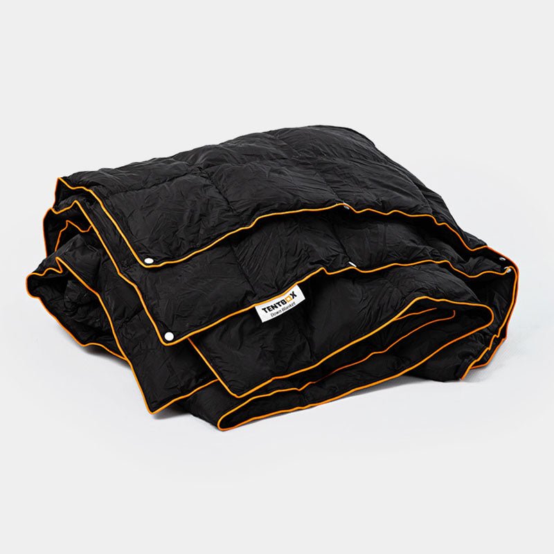 Folded black quilted synthetic down blanket with orange trim and TentBox logo.